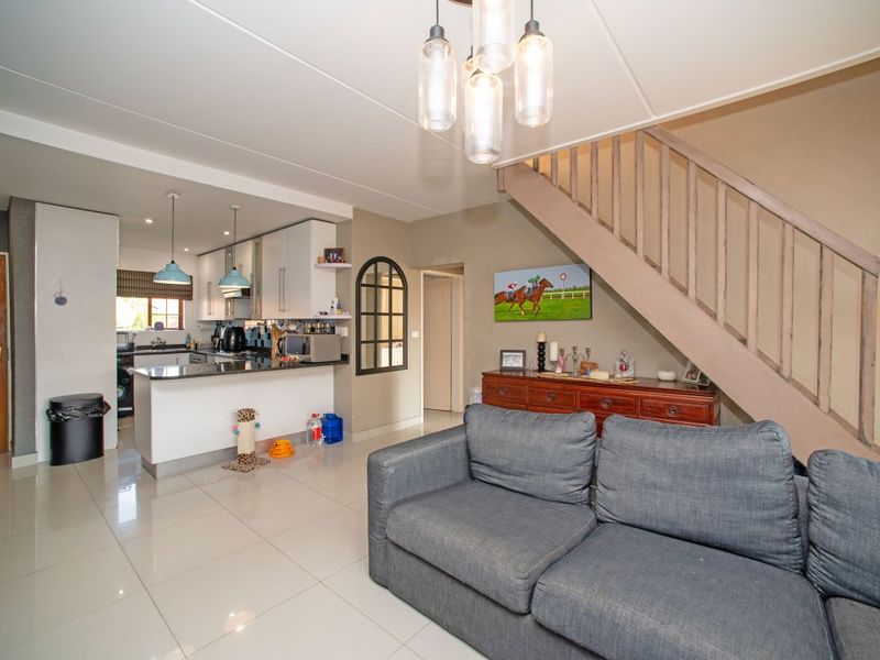 Open-plan living area featuring a modern kitchen with granite countertops, tiled flooring, and a staircase leading to the upper level.