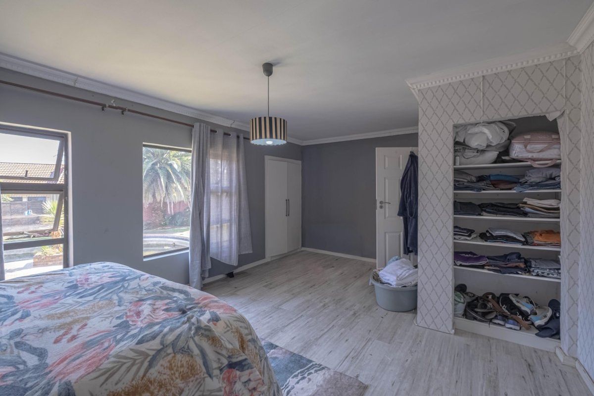 Spacious bedroom featuring laminate flooring, built-in wardrobe storage, and large windows providing natural light and garden views.