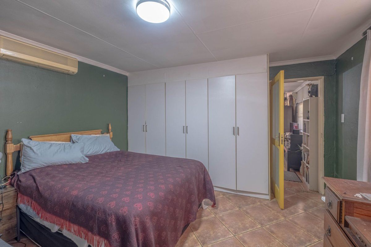 Bedroom featuring built-in cupboards, tiled flooring, and a wall-mounted air conditioning unit.
