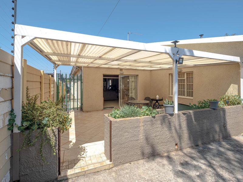A covered outdoor patio area featuring tiled flooring, built-in planter boxes, and direct access to the interior through a sliding glass door.