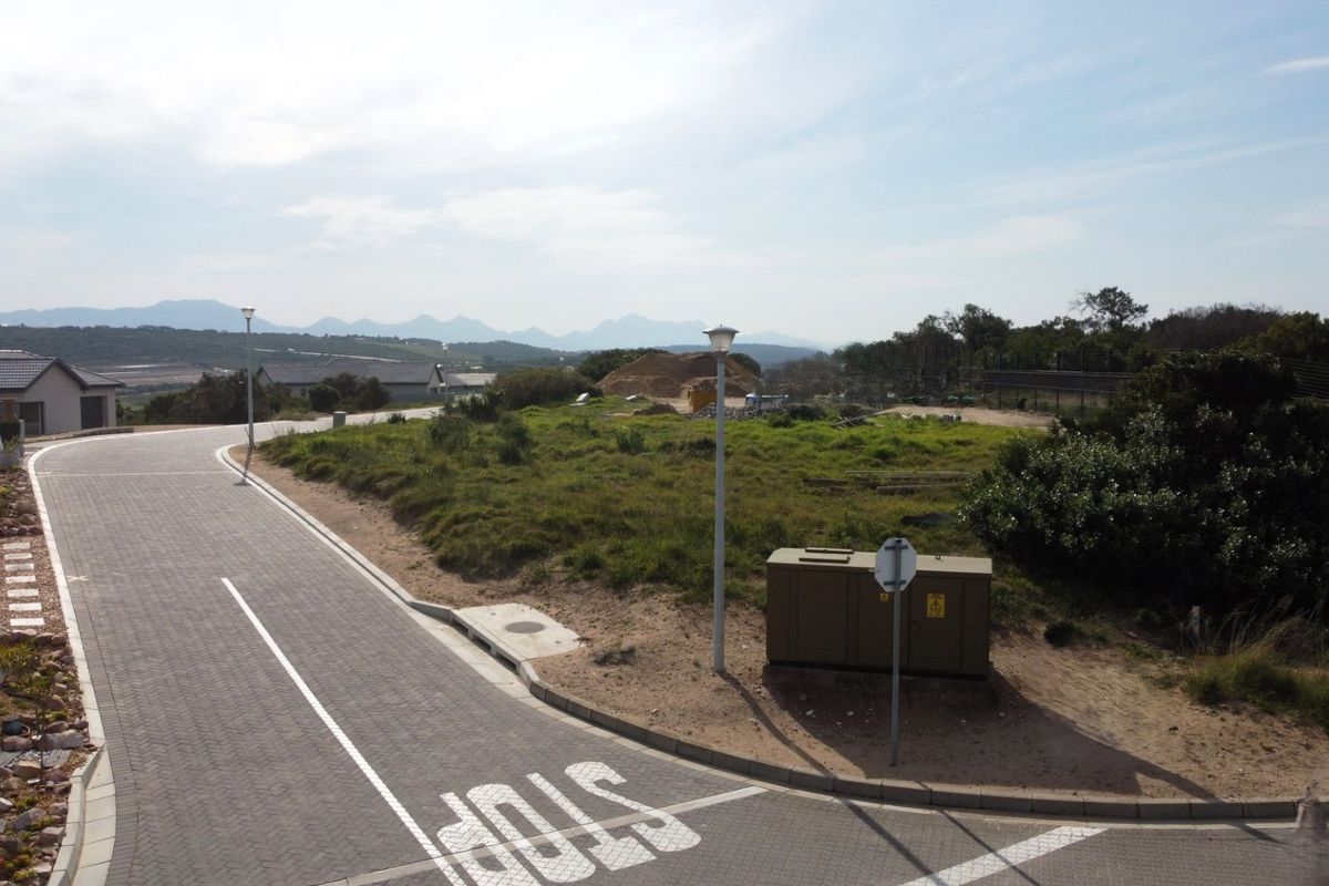 A street-level view of a residential development showing paved roads, street lighting, and utility infrastructure with surrounding landscape views.