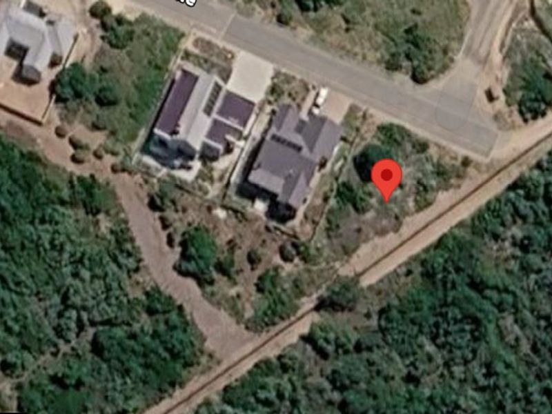 Aerial view of a vacant residential plot situated in a developed neighborhood with established road access.