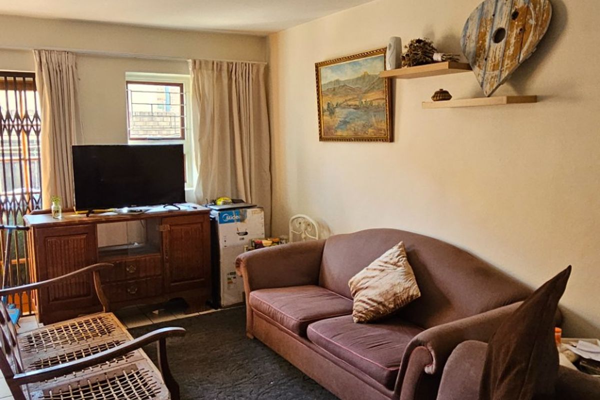 A comfortable living room featuring tiled flooring and a security gate leading to the exterior, providing a functional and lived-in space.