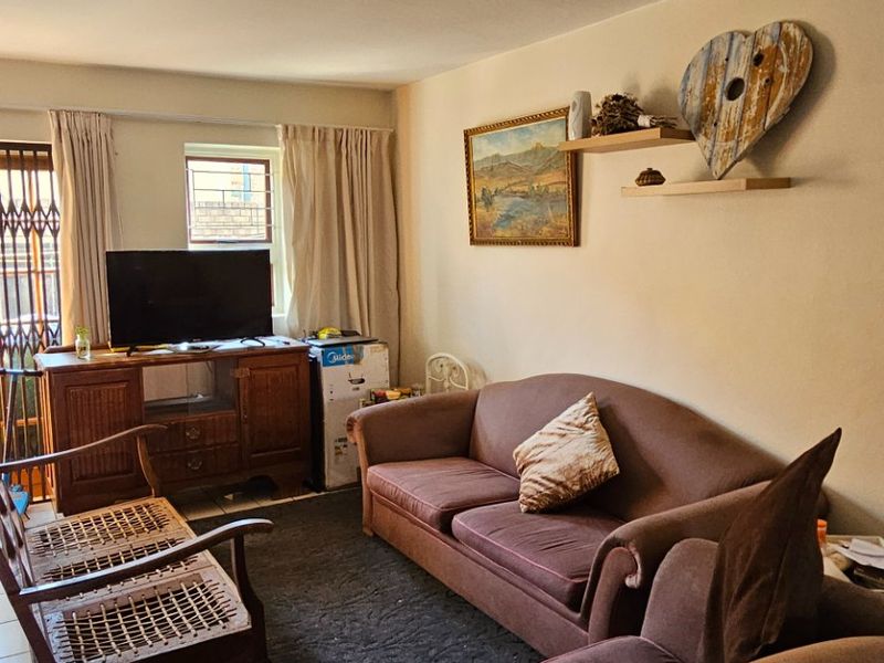 A comfortable living room featuring tiled flooring and a security gate leading to the exterior, providing a functional and lived-in space.