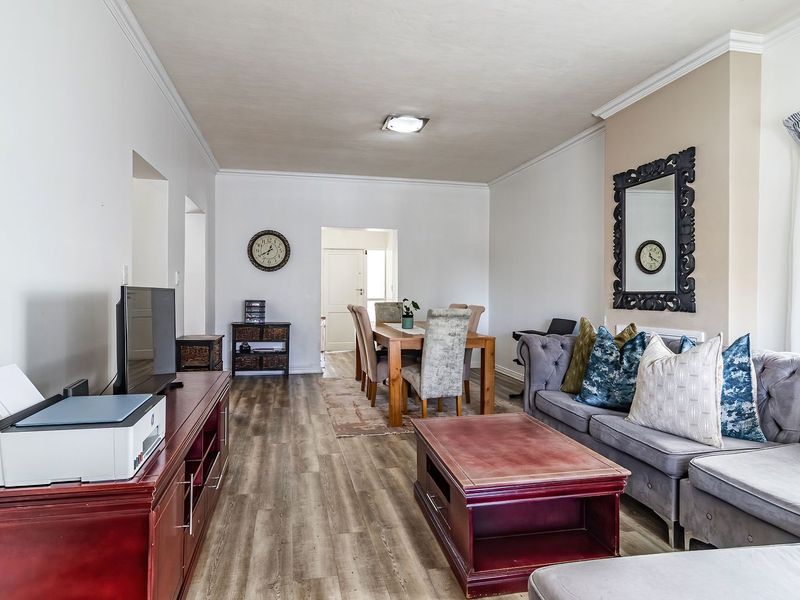Open-plan living and dining area featuring laminate flooring, crown molding, and neutral wall finishes, providing a versatile space for relaxation and entertaining.