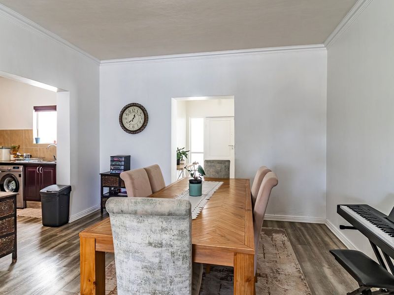 Open plan dining area featuring laminate flooring and crown molding, with a view into the adjacent kitchen space.