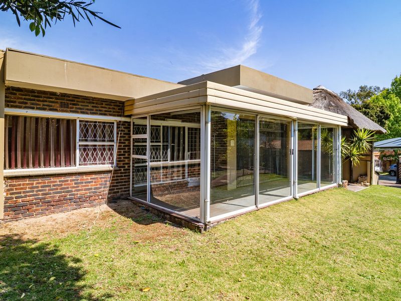 Rear view of the property featuring a brick facade and an enclosed patio area with sliding glass doors overlooking the garden.