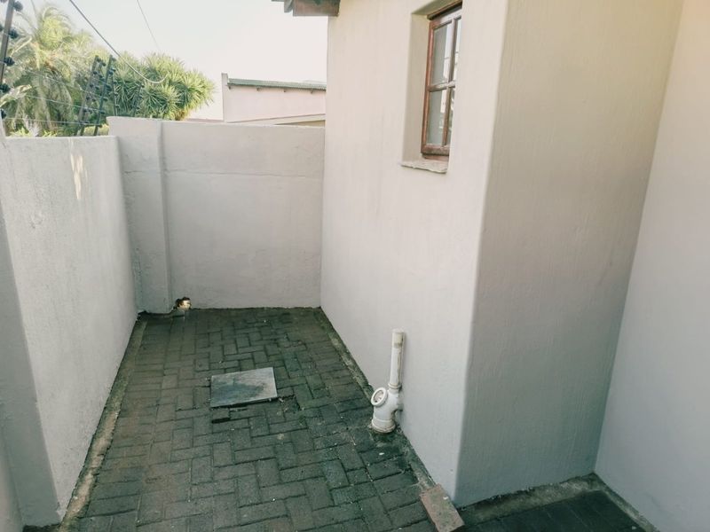 An outdoor utility or service area featuring paved flooring, a boundary wall with electric fencing, and visible plumbing infrastructure.