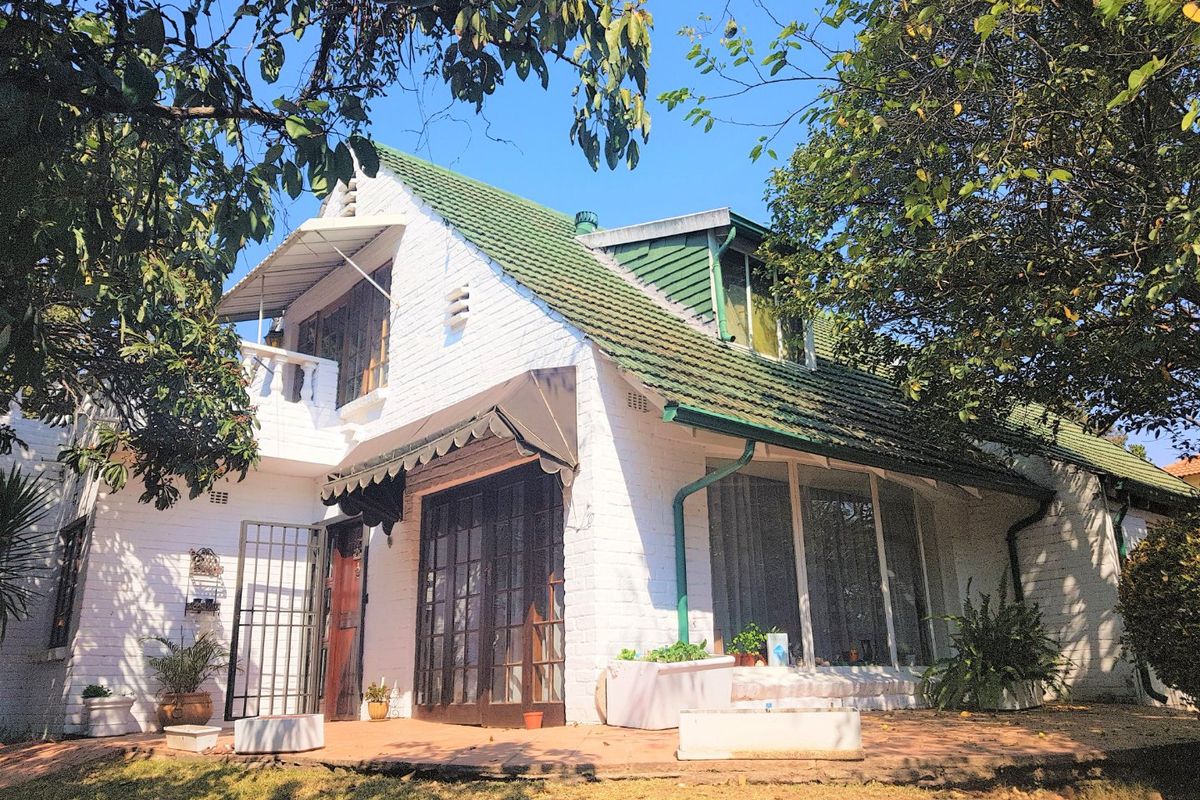 Rear view of a white painted brick house featuring a tiled roof, dormer window, and a covered patio area.