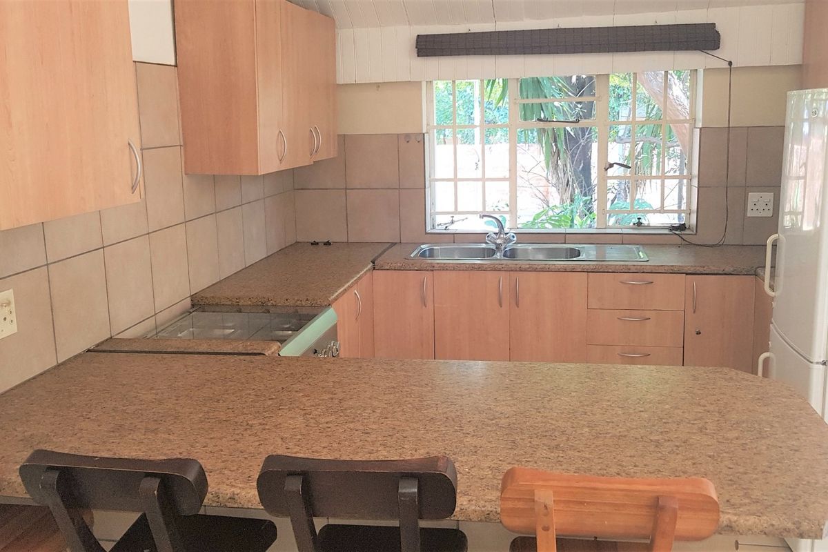 Functional kitchen featuring laminate cabinetry, granite-look countertops, a double bowl sink, and a tiled backsplash with a window overlooking the garden.