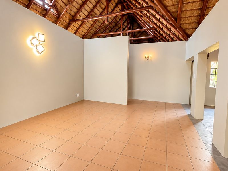 Spacious living area featuring a high vaulted thatched ceiling with exposed timber trusses and neutral tiled flooring.