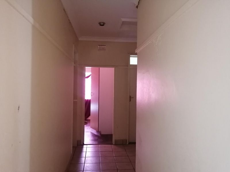 A vacant interior hallway featuring tiled flooring and coved ceilings, providing access to adjacent rooms.