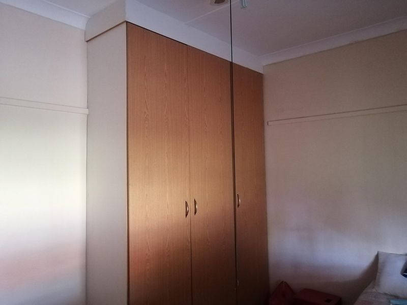 A bedroom featuring a full-height built-in wooden wardrobe with classic coving and picture rail detailing.