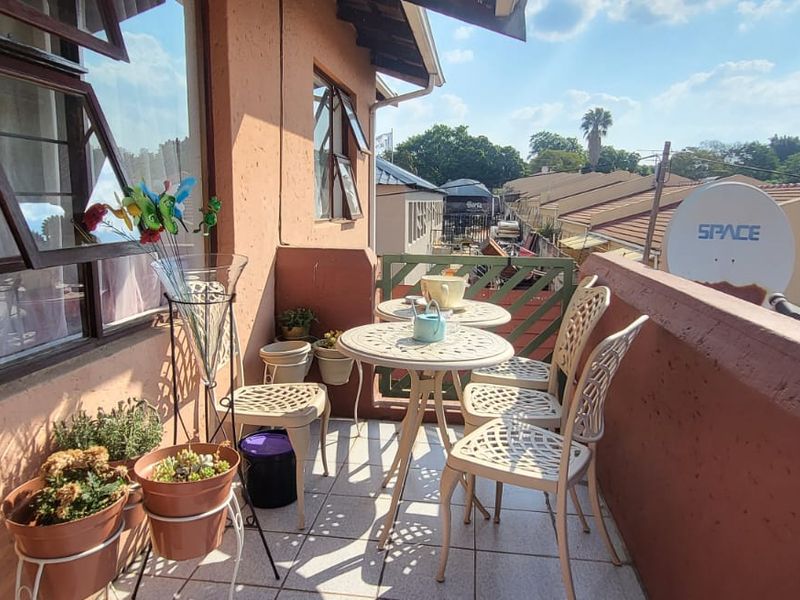 A compact balcony featuring tiled flooring and a metal balustrade, offering an outdoor space with views of the surrounding residential area.
