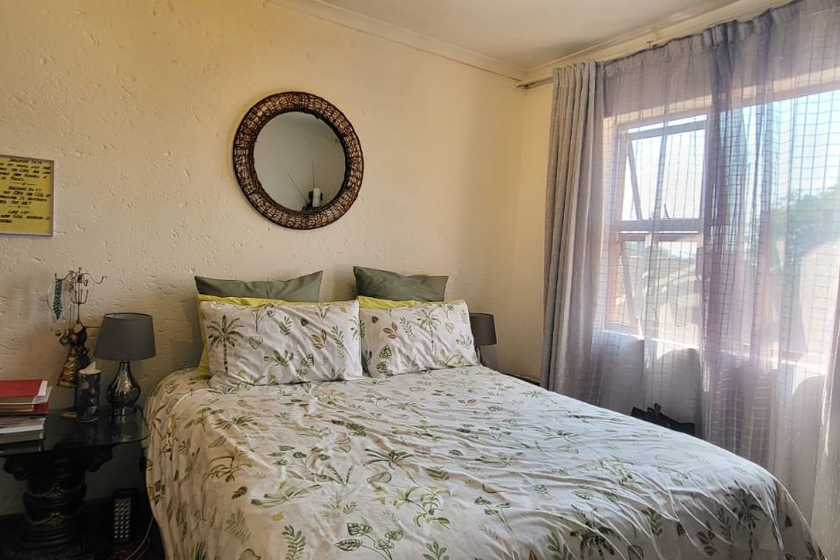 A standard bedroom featuring textured walls, a window with curtain rails, and natural light.
