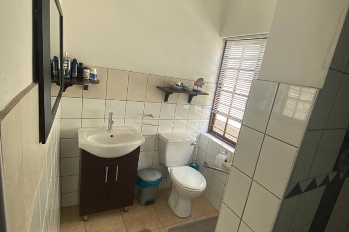 A functional bathroom featuring a vanity cabinet with basin, toilet, and neutral wall and floor tiling.