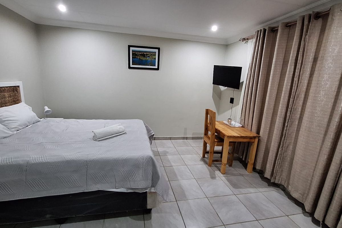 A functional bedroom featuring neutral wall tones, tiled flooring, and recessed lighting, providing a clean and simple living space.