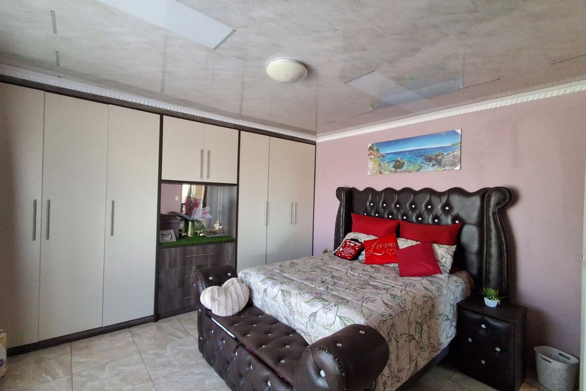 Spacious bedroom featuring extensive built-in cupboards, tiled flooring, and a decorative coved ceiling.
