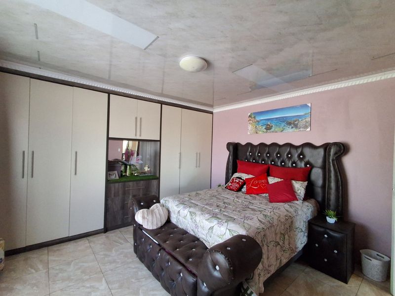 Spacious bedroom featuring extensive built-in cupboards, tiled flooring, and a decorative coved ceiling.