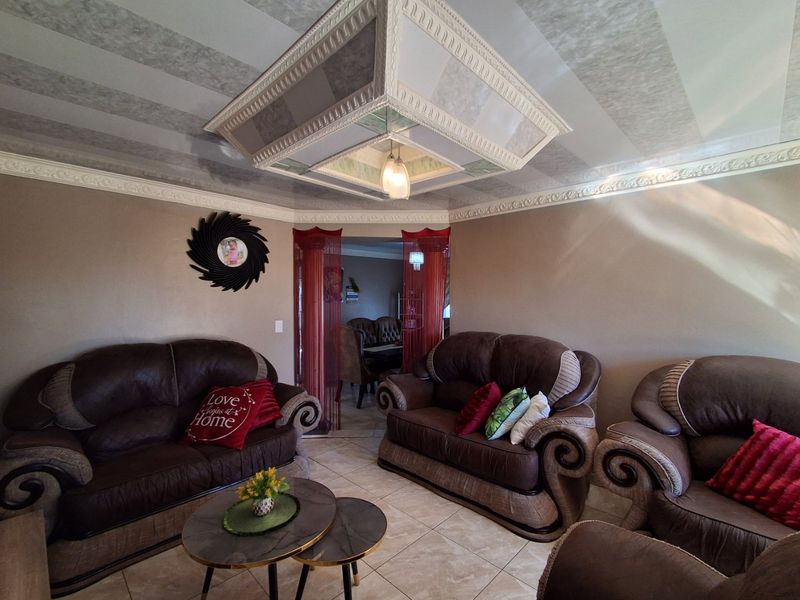A living room featuring ceramic floor tiles, decorative crown molding, and a prominent coffered ceiling design with central lighting.