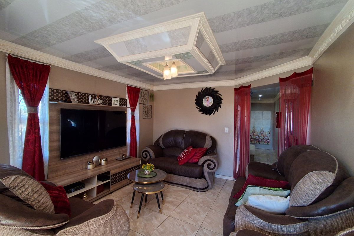 A cozy living room featuring tiled flooring, a decorative ceiling feature, and a built-in media unit.