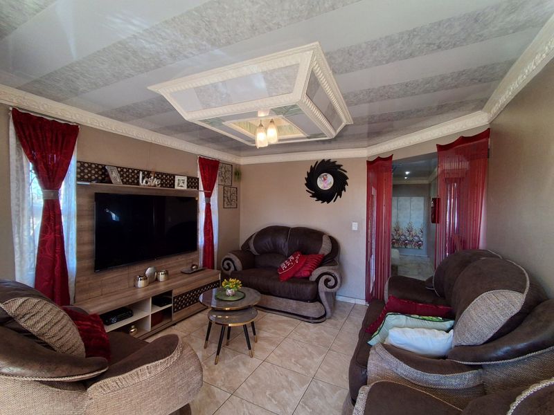 A cozy living room featuring tiled flooring, a decorative ceiling feature, and a built-in media unit.