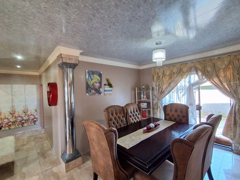 A dining room featuring tiled flooring, a decorative column, and a sliding glass door with security gate leading to the exterior.