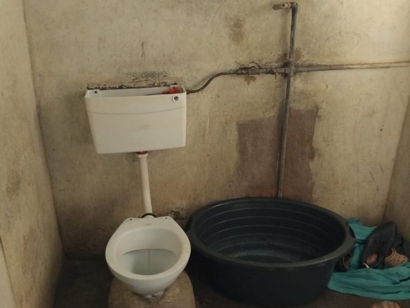 A basic bathroom space featuring a toilet and exposed plumbing, requiring significant renovation and cosmetic updates to improve the condition of the walls and finishes.