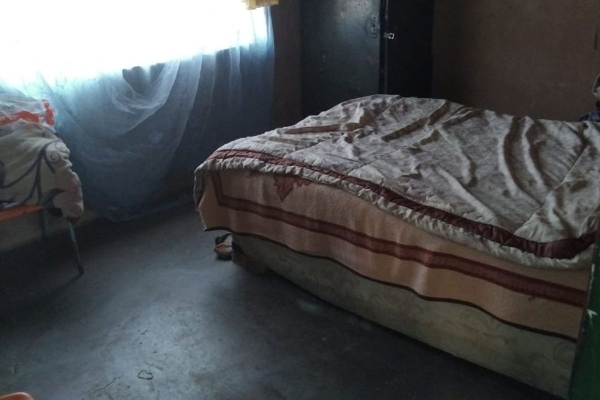 A bedroom featuring a window with natural light, concrete flooring, and basic wall finishes.