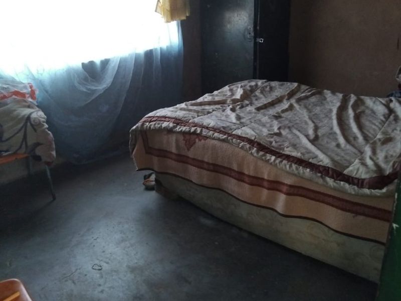 A bedroom featuring a window with natural light, concrete flooring, and basic wall finishes.