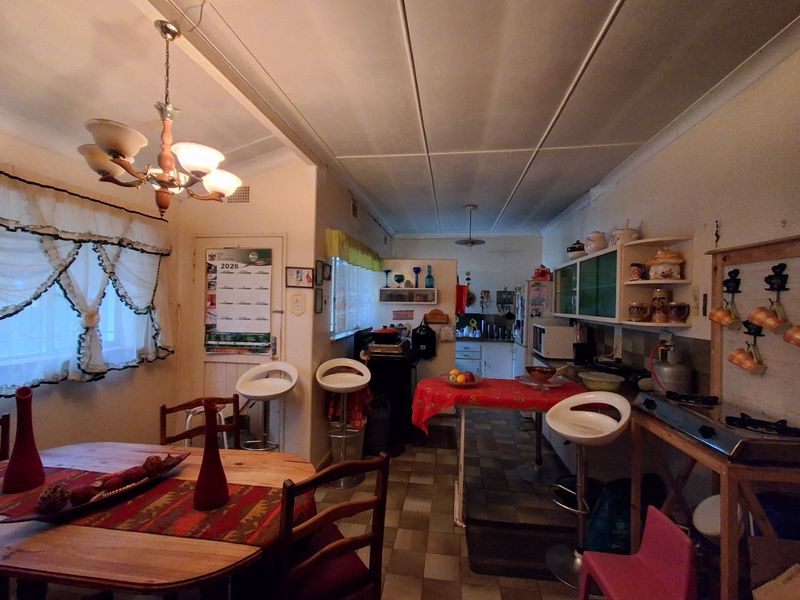 Open plan kitchen and dining area featuring tiled flooring, built-in cabinetry, and traditional pendant lighting, offering a functional layout with potential for modernization.