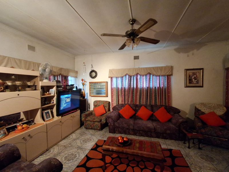 A living room featuring tiled flooring and a ceiling fan, presenting an opportunity for modernization and aesthetic updates.