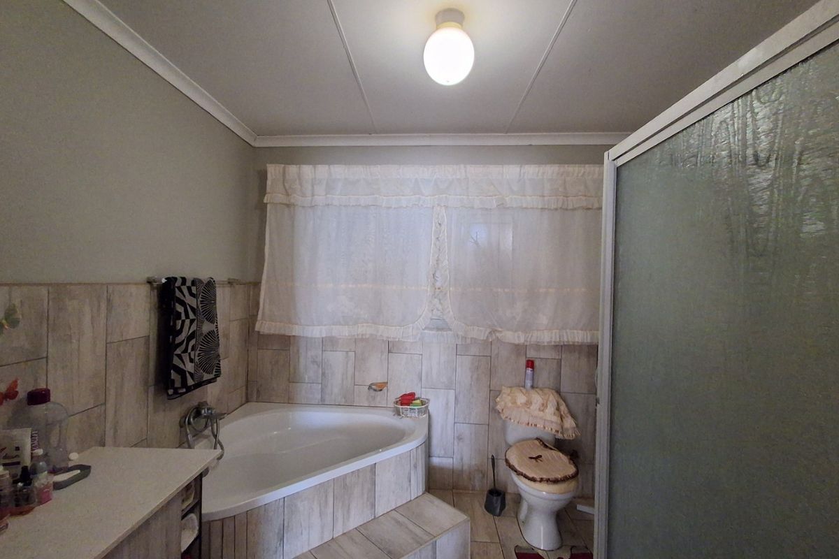 A functional bathroom featuring a corner bathtub, separate shower enclosure, toilet, and vanity cabinet with neutral tiled finishes.