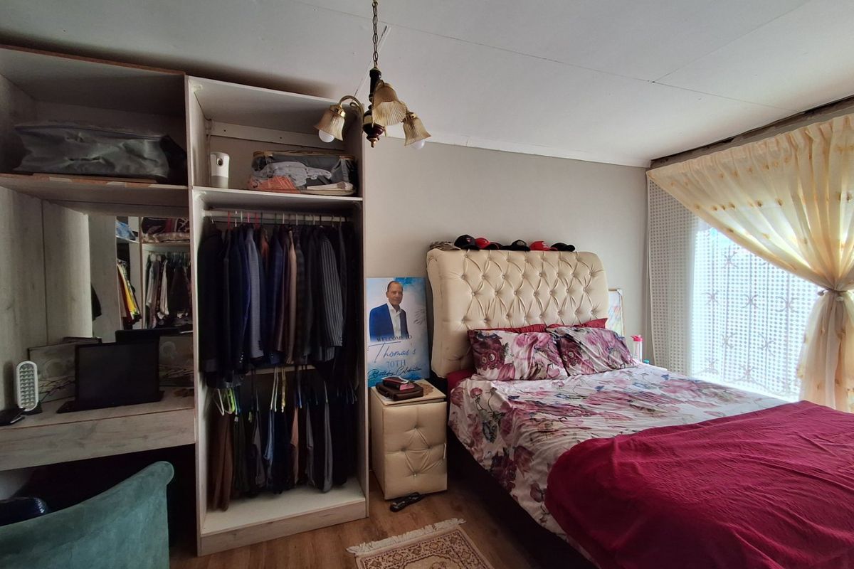 A bedroom featuring laminate flooring, a built-in wardrobe, and a central ceiling light fixture.