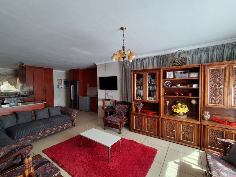 Open-plan living area featuring tiled flooring and a connected kitchen with built-in cabinetry and a central island, offering a functional layout.