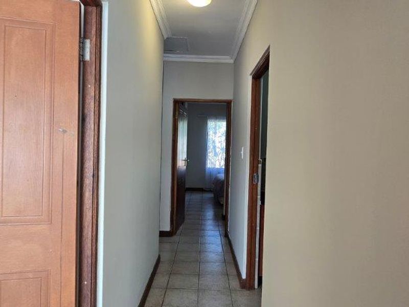 A functional hallway featuring tiled flooring and wooden door frames, providing access to multiple rooms within the townhouse.
