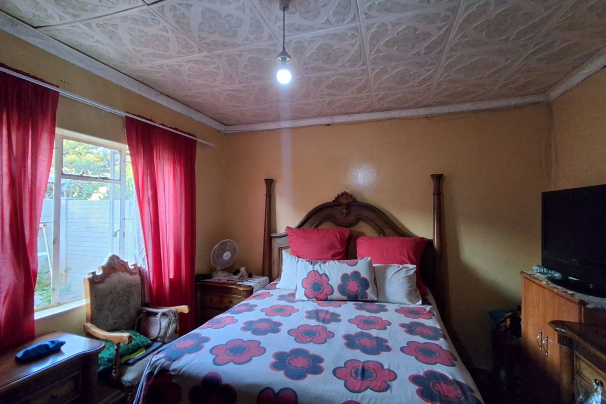 A bedroom featuring a patterned ceiling, pendant lighting, and a window, offering a dated aesthetic that could be updated with modern finishes.