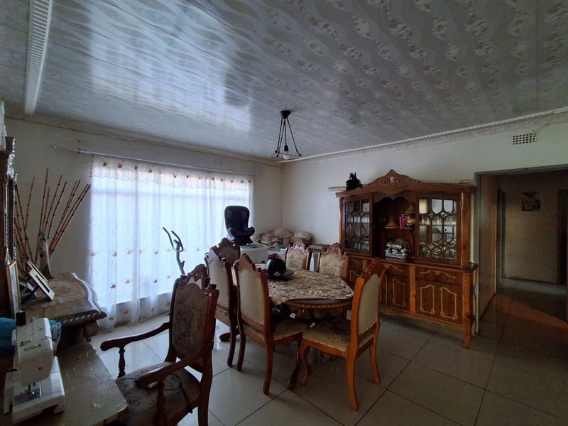 A dining room featuring tiled flooring and decorative ceiling panels, offering a functional space that could benefit from modern updates to finishes.
