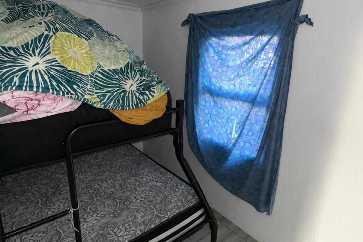 A compact bedroom featuring tiled flooring and a ceiling light fixture, providing a functional sleeping space.