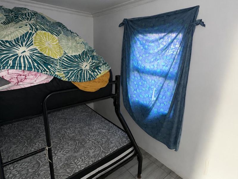 A compact bedroom featuring tiled flooring and a ceiling light fixture, providing a functional sleeping space.