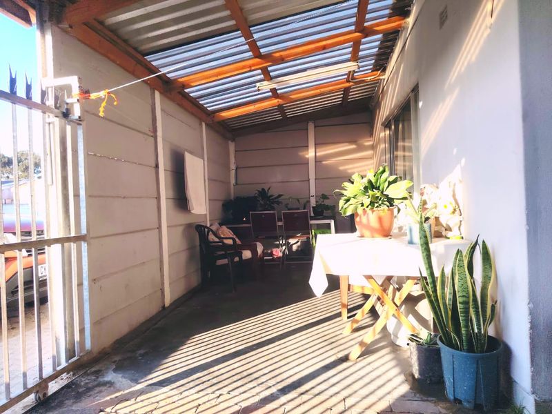 A covered outdoor patio area featuring a translucent roof, precast concrete walls, and paved flooring, providing a functional space for outdoor relaxation.