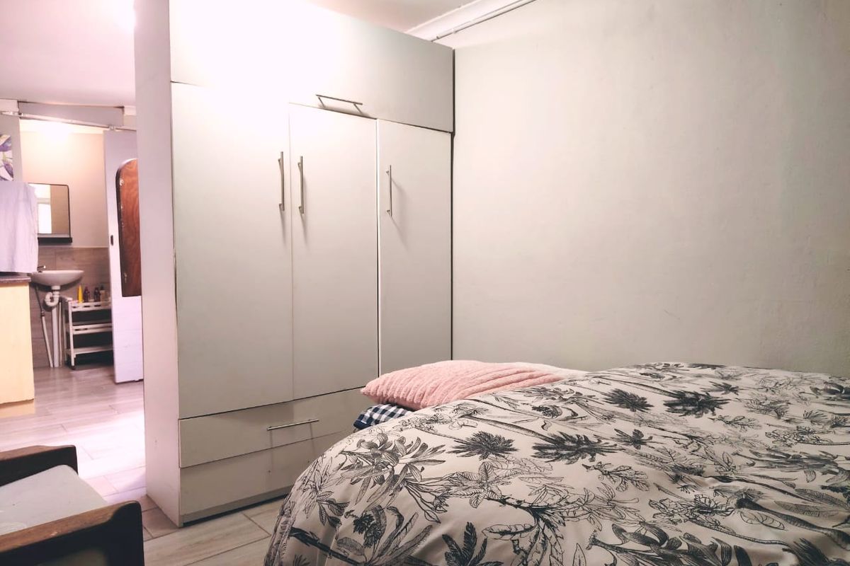 A bedroom featuring a built-in wardrobe and tiled flooring, with an adjacent view into a bathroom area.