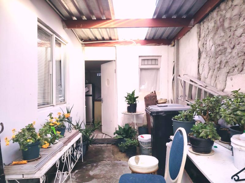 A covered outdoor patio area featuring a corrugated metal roof, exposed steel beams, and a rustic stone masonry wall.