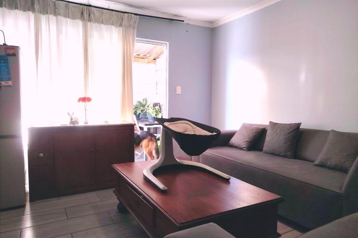A living room featuring tiled flooring and a sliding door leading to an outdoor area, providing natural light to the space.