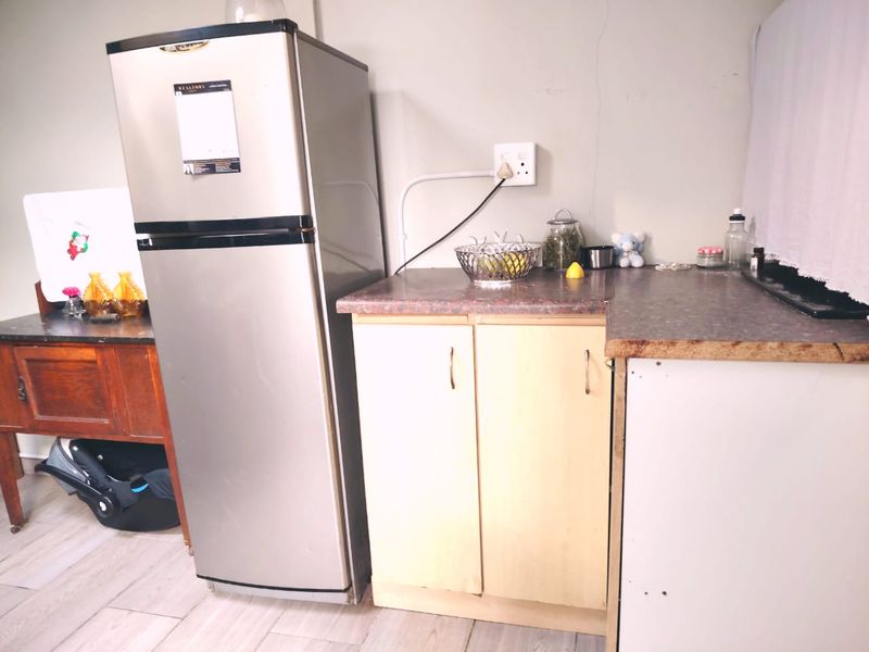 A compact kitchen area featuring laminate countertops and basic base cabinetry, showing signs of wear and minor wall damage.