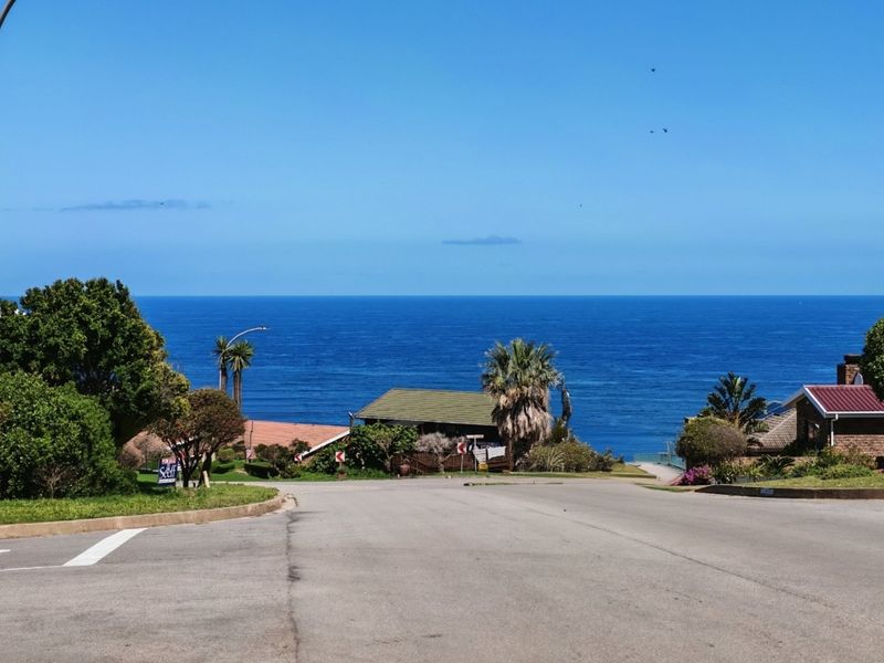 A clear street view looking down a residential road towards the ocean, showcasing the coastal location and neighbourhood approach.