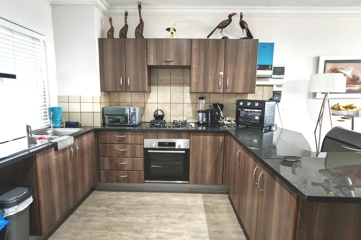 A functional kitchen featuring wood-finish cabinetry, granite countertops, a built-in oven, gas hob, and tiled backsplash with ample workspace.