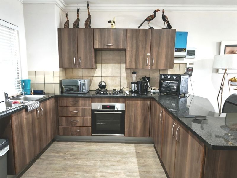 A functional kitchen featuring wood-finish cabinetry, granite countertops, a built-in oven, gas hob, and tiled backsplash with ample workspace.