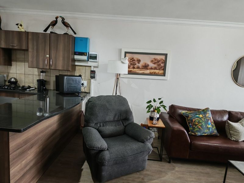 Open-plan living area featuring a kitchen with dark wood cabinetry, granite countertops, and a gas hob, seamlessly flowing into the lounge space.