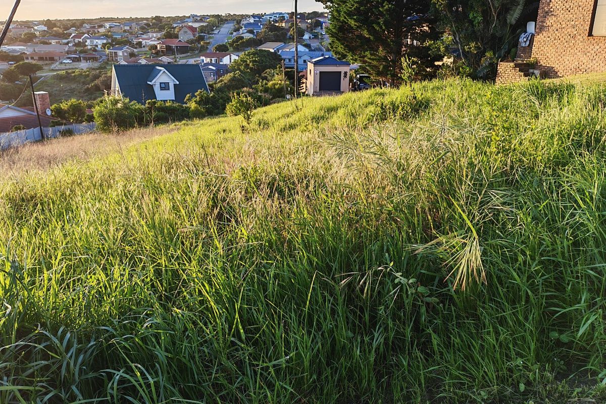 A view of the sloped vacant residential land overlooking the surrounding neighborhood and suburban landscape.